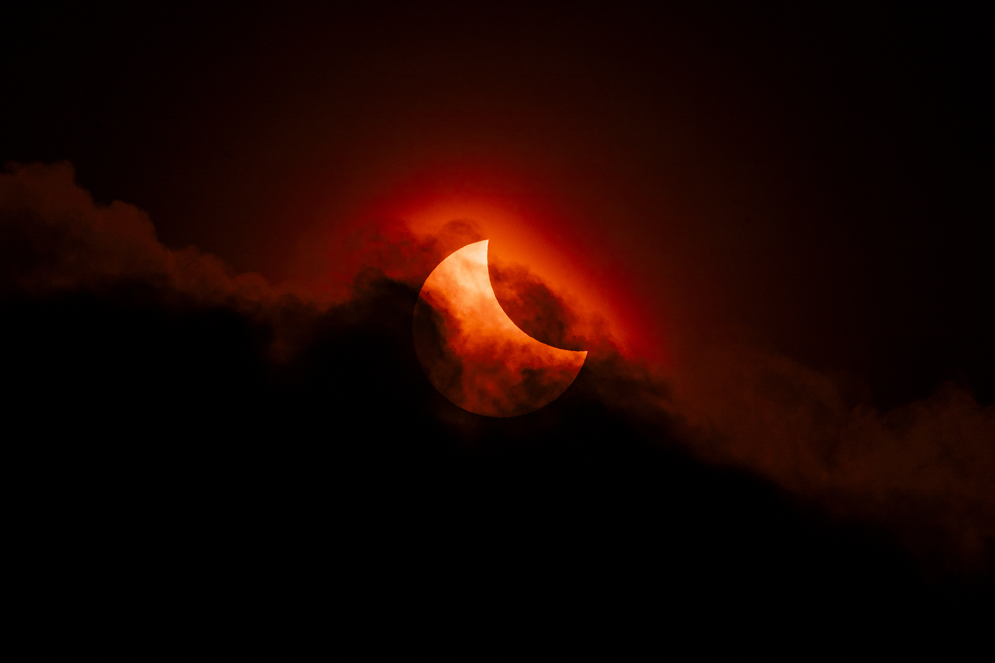 The 2025 partial eclipse is seen as clouds almost block the sun creating a spectacular and blood-coloured spectacle